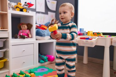 Sevimli beyaz bebek, anaokulunda kendinden emin bir şekilde gülümsüyor.