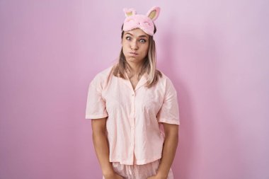 Sarışın, beyaz, uyku maskesi takan ve komik yüzlü pijama şişiren kadın. Havayla şişmiş ağız, çılgın bir ifade.. 