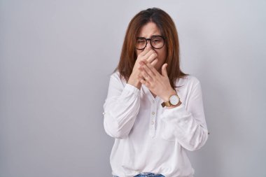 Esmer kadın, izole edilmiş beyaz arka planda duruyor. Kokuşmuş ve iğrenç bir koku alıyor. Dayanılmaz bir koku. Kötü kokuyor. 