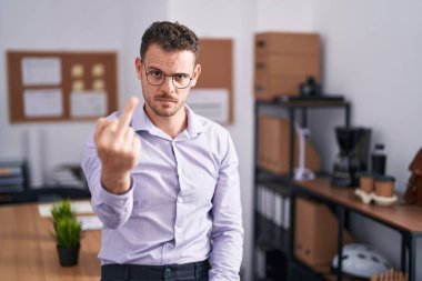 Young hispanic man at the office showing middle finger, impolite and rude fuck off expression 