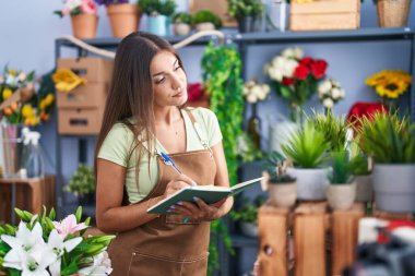 Çiçekçide deftere yazan güzel İspanyol bir çiçekçi kadın.