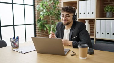 Genç Arap iş adamı, ofiste baterist jestleri yaparak müzik dinliyor.