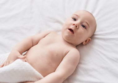 Adorable caucasian baby lying on bed at bedroom