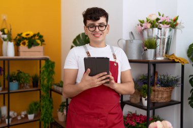 Non binary man florist smiling confident using touchpad at flower shop