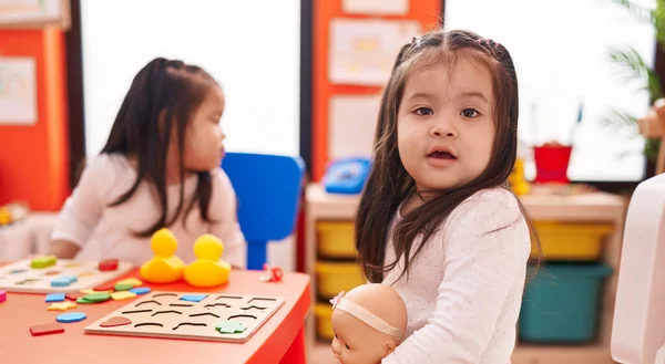 可愛いです双子の女の子遊びとともに数学パズルゲーム上のテーブルの上に座って幼稚園 — ストック写真