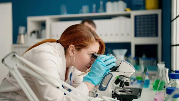 实验室显微镜下穿着科学制服的男男女女 — 图库照片