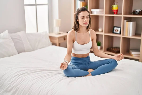 年轻美丽的惊慌失措的女人坐在床上做瑜伽练习 — 图库照片