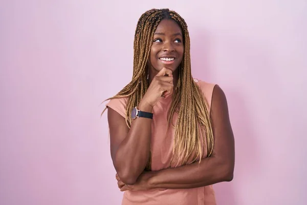 Африканская Американка Плетеными Волосами Стоящая Розовом Фоне Рукой Подбородке Думает — стоковое фото