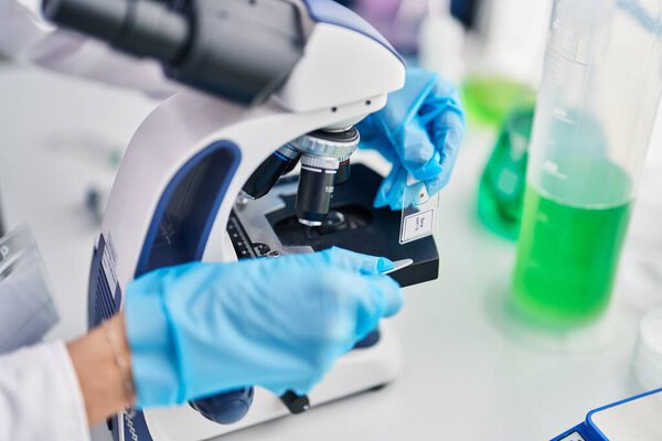 Молодая красивая латиноамериканка-ученый пользуется микроскопом в лаборатории