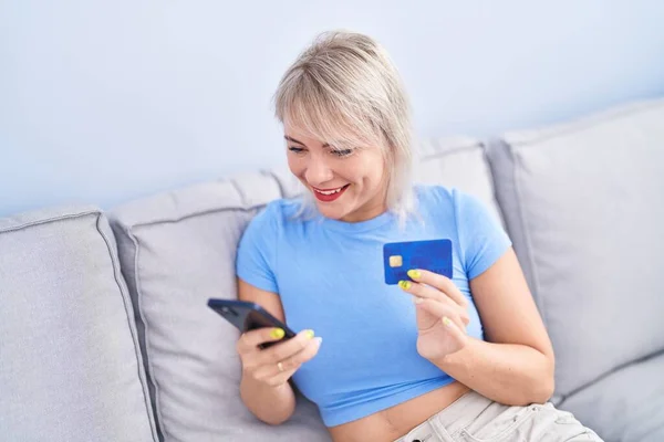 Ung Blond Kvinna Som Använder Smartphone Och Kreditkort Sitter Soffan — Stockfoto