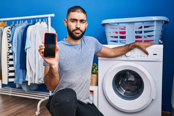 Middle East Man Beard Showing Smartphone Screen Washing Machine Skeptic — Φωτογραφία Αρχείου