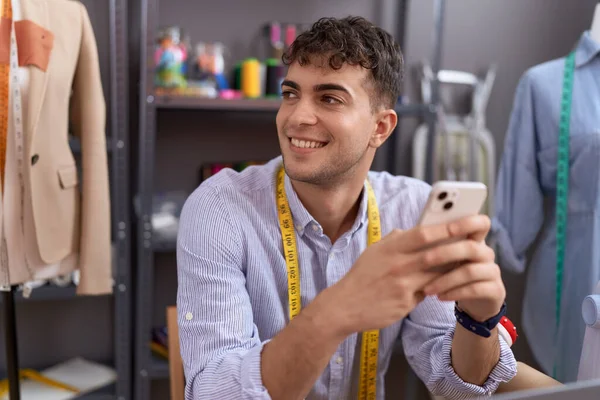 Νεαρός Ισπανός Ράφτης Χαμογελά Αυτοπεποίθηση Χρησιμοποιώντας Smartphone Στο Ατελιέ — Φωτογραφία Αρχείου