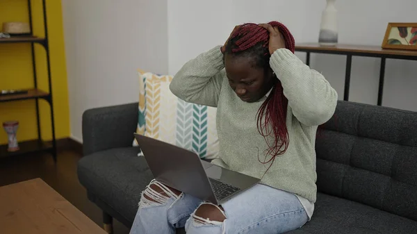 自宅で心配そうな表情を持つラップトップを使用して編組髪を持つアフリカの女性 — ストック写真