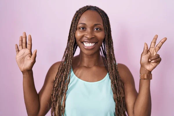 非洲裔美国妇女站在粉红的背景上 用八号手指指指指点点 自信而快乐地微笑着 — 图库照片