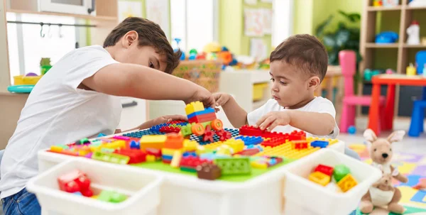 stock image Adorable boys playing with construction blocks sitting on table at kindergarten