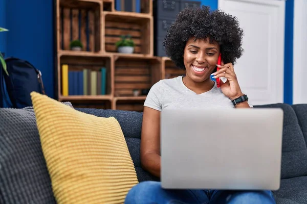 African American Woman Talking Smartphone Using Laptop Home — стокове фото