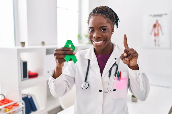 美しい黒の医師の女性は幸せな顔を持つアイデアや質問を指差す指で驚いて精神衛生意識のためのサポートグリーンリボンを保持し ナンバーワン — ストック写真
