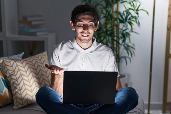Jovem Hispânico Usando Laptop Casa Noite Apontando Para Lado Com — Fotografia de Stock