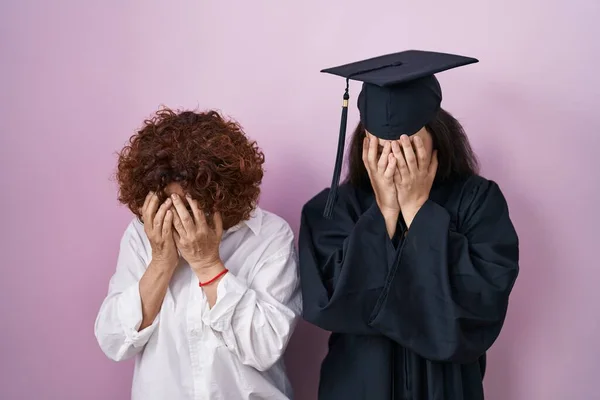 泣きながら手で顔を覆う悲しい表情で卒業キャップと式のローブを着たヒスパニック系の母親と娘 うつ病の概念 — ストック写真