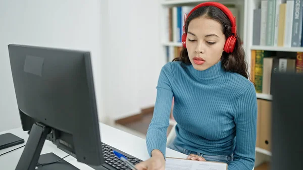 年轻美丽的惊慌失措的女学生带着耳机在大学教室里用电脑记笔记 — 图库照片