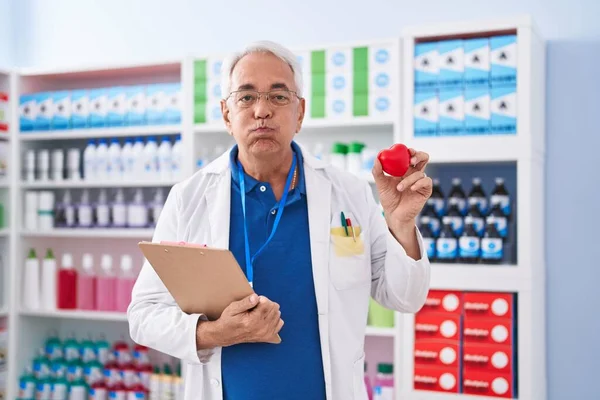 Мужчина Средних Лет Седыми Волосами Работает Аптеке Держа Красное Сердце — стоковое фото