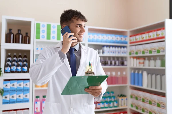 Young Hispanic Man Pharmacist Talking Smartphone Reading Document Pharmacy — Stock Fotó