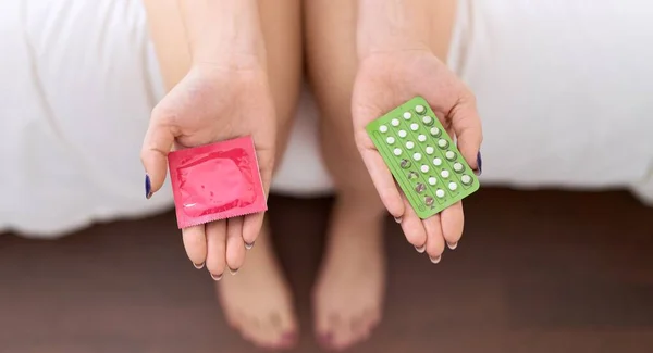 Młoda Piękna Kobieta Trzyma Tabletki Antykoncepcyjne Prezerwatywy Sypialni — Zdjęcie stockowe