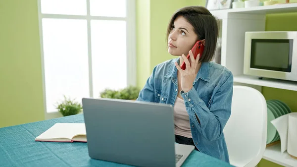 年轻的高加索女人在家里用笔记本电脑用智能手机聊天 — 图库照片