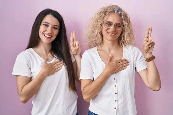 Mother Daughter Standing Together Pink Background Smiling Swearing Hand Chest — Stock Photo, Image