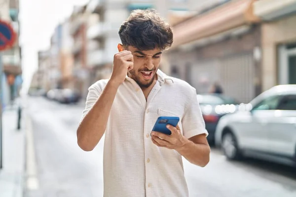 Młody Arabski Człowiek Pomocą Smartfona Wyrazem Zwycięzcy Ulicy — Zdjęcie stockowe