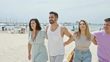 Sahilde yürürken birbirine sarılan bir grup insan.