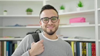 Kütüphanede gözlük takarak gülümseyen İspanyol öğrenci.