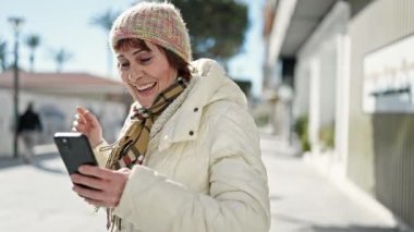 Sokakta akıllı telefon dansı yaparak gülümseyen olgun İspanyol kadın.