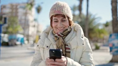 Sokakta akıllı telefon kullanan, kendine güvenen, olgun İspanyol kadın.