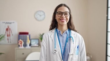 Genç, güzel İspanyol kadın doktor gülümsüyor klinikte elleriyle kalp hareketi yapıyor.