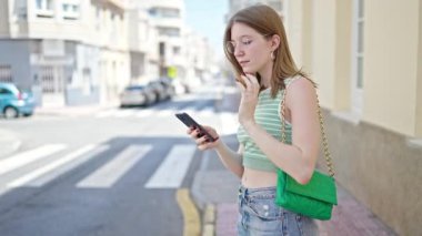 Akıllı telefon kullanan genç sarışın kadın caddede taksi istiyor.