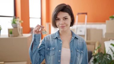 Yeni evinde kendine güvenen beyaz bir kadın gülümsüyor.