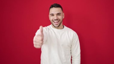 İzole edilmiş kırmızı arka planda gülümseyen İspanyol genç adam.