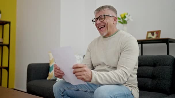 Orta Yaşlı Kır Saçlı Evrak Okuyan Adam Evdeki Kanepede Oturuyor — Stok video