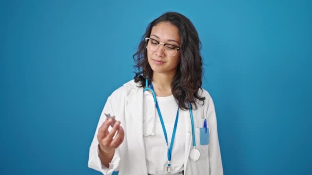Junge Schöne Hispanische Ärztin Hält Pillen Über Isolierten Blauen Wandhintergrund — Stockvideo