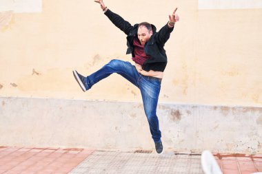 Young hispanic man smiling confident jumping at street