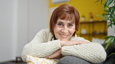 Evdeki koltukta oturan, kendine güvenen, olgun İspanyol kadın.