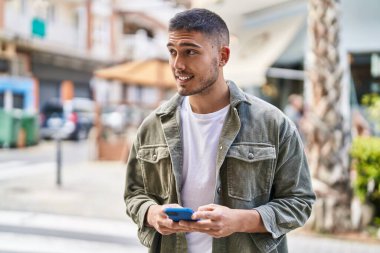 Sokakta akıllı telefon kullanan, kendine güvenen genç bir İspanyol.