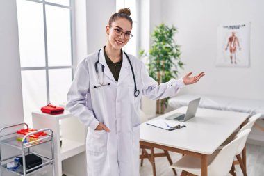 Young woman wearing doctor uniform standing at clinic