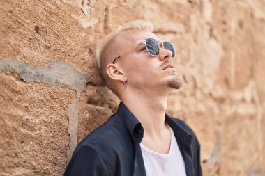 Sokakta ciddi bir ifadeyle duran beyaz bir genç.