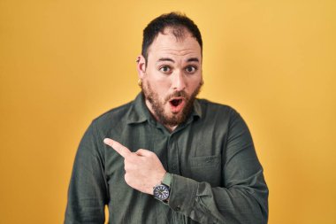 Ayrıca sarı arka planda dikilen sakallı, iri yarı, ağzı açık, parmakları yana dönük, ağzı açık, şaşırmış bir adam.. 