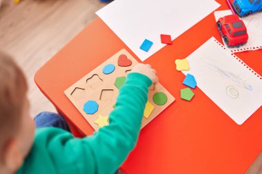 Anaokulunda masada oturmuş matematik oyunu oynayan sevimli beyaz çocuk.