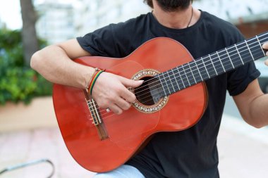 Genç İspanyol müzisyen parkta klasik gitar çalıyor.