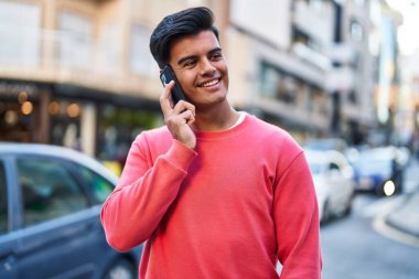 Genç İspanyol adam gülümsüyor. Kendine güveniyor. Sokakta akıllı telefondan konuşuyor.