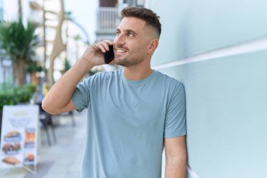 Genç İspanyol adam gülümsüyor. Kendine güveniyor. Sokakta akıllı telefondan konuşuyor.